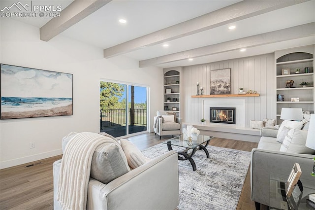 living room with built in shelves, beamed ceiling, and hardwood / wood-style floors