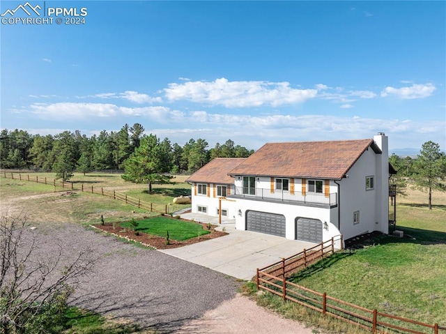 view of front of house featuring a garage, a rural view, and a front lawn