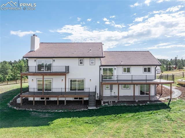 rear view of property with a yard and a balcony