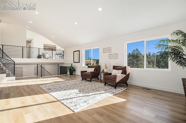 sitting room with high vaulted ceiling and wood-type flooring