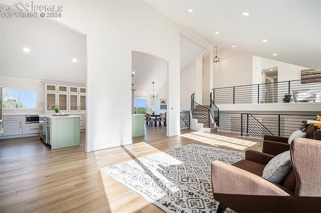 living room with light hardwood / wood-style floors, a chandelier, and high vaulted ceiling