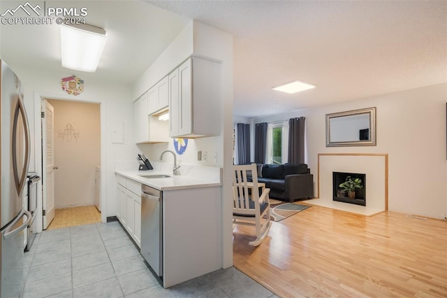 kitchen featuring white cabinets, light hardwood / wood-style floors, sink, and stainless steel appliances