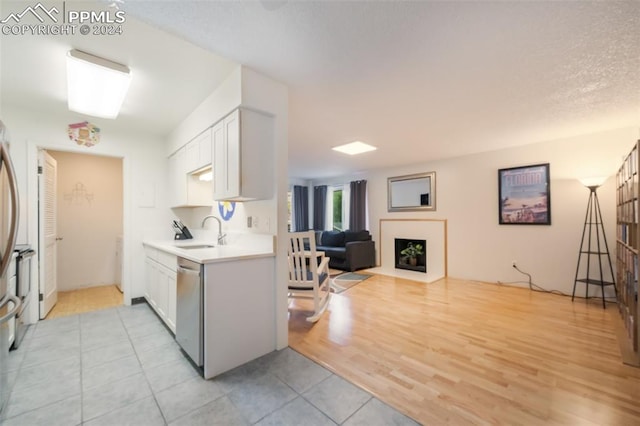 kitchen featuring white cabinets, light hardwood / wood-style flooring, sink, and stainless steel dishwasher