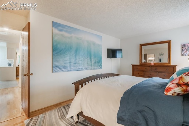 bedroom featuring a textured ceiling and light hardwood / wood-style floors