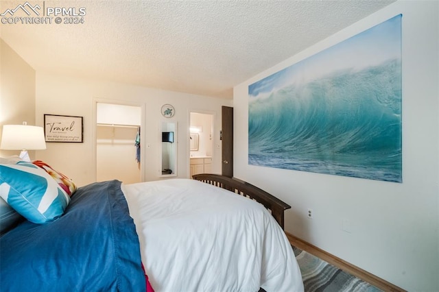 bedroom featuring wood-type flooring, a closet, a textured ceiling, ensuite bath, and a spacious closet