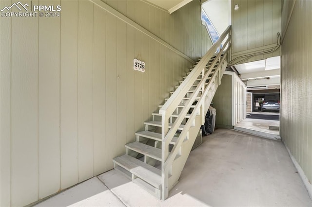 stairway with wood walls and concrete flooring