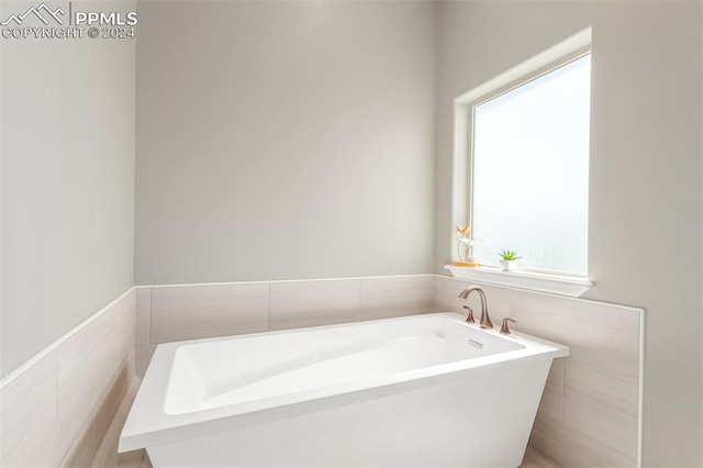 bathroom featuring tile walls and a bath