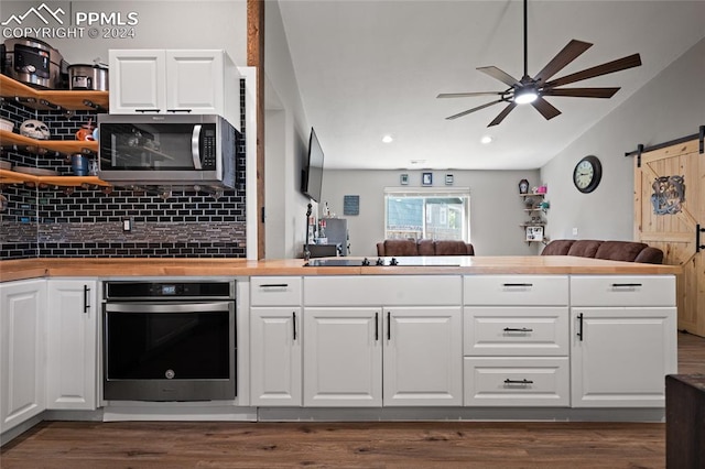 kitchen featuring a barn door, white cabinetry, ceiling fan, and stainless steel appliances