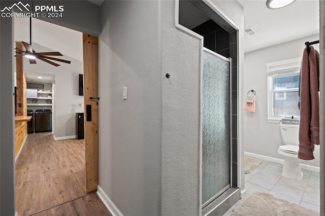 bathroom with wood-type flooring, ceiling fan, a shower with door, and toilet