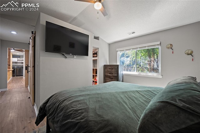 bedroom with wood-type flooring, lofted ceiling, ceiling fan, and a textured ceiling