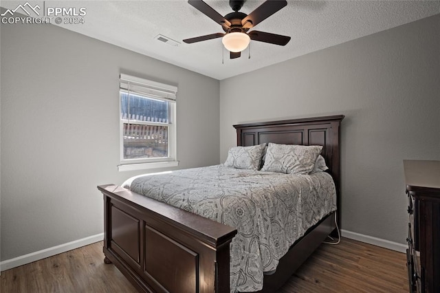 bedroom with ceiling fan, dark hardwood / wood-style floors, and a textured ceiling