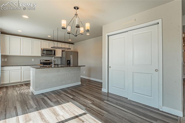 kitchen with pendant lighting, light hardwood / wood-style floors, white cabinets, stainless steel appliances, and a center island with sink