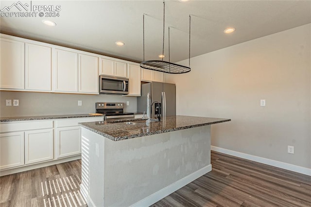 kitchen featuring white cabinets, a center island with sink, appliances with stainless steel finishes, and dark hardwood / wood-style flooring