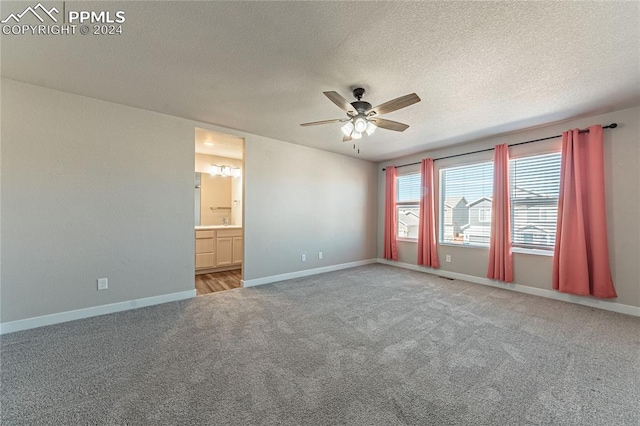 unfurnished bedroom with ceiling fan, a textured ceiling, carpet floors, and ensuite bathroom