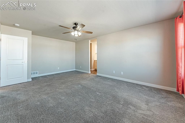 spare room featuring dark carpet and ceiling fan