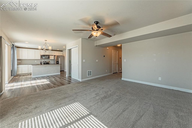 unfurnished living room featuring sink, ceiling fan with notable chandelier, and light hardwood / wood-style floors