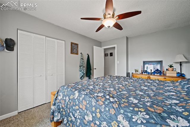 bedroom with a closet, ceiling fan, carpet flooring, and a textured ceiling