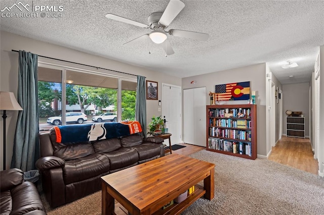 living room featuring light hardwood / wood-style floors, a textured ceiling, and ceiling fan