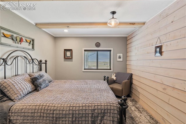 bedroom with beam ceiling and wooden walls