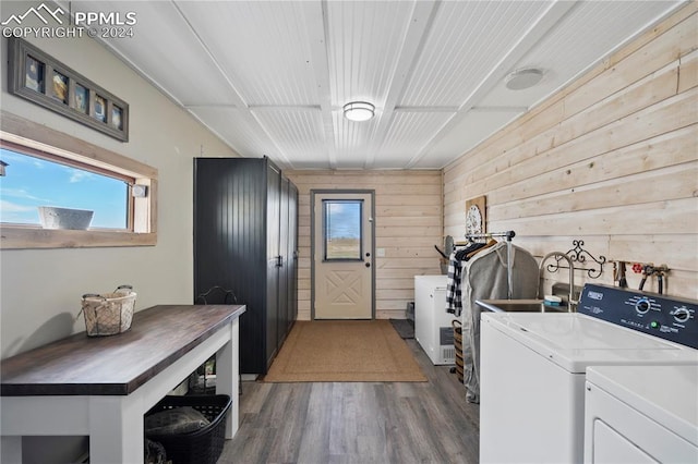 laundry room featuring washing machine and clothes dryer, wood walls, dark wood-type flooring, and sink