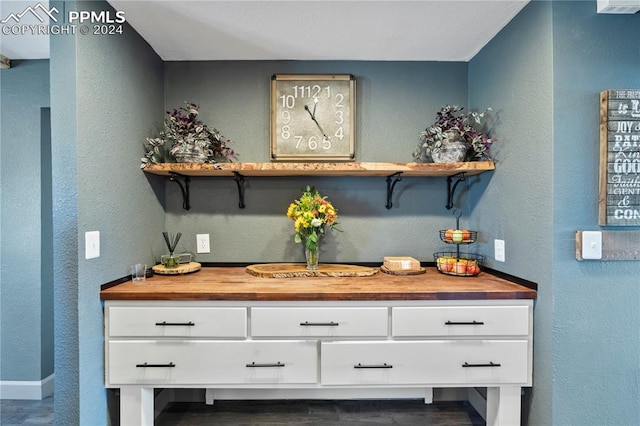 bar with wooden counters and white cabinetry