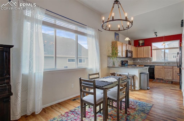 dining area with light wood-type flooring, an inviting chandelier, and a healthy amount of sunlight