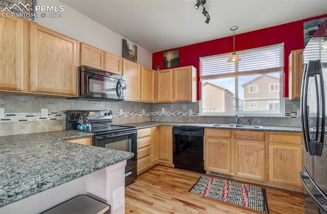 kitchen with backsplash, sink, black appliances, light hardwood / wood-style flooring, and hanging light fixtures