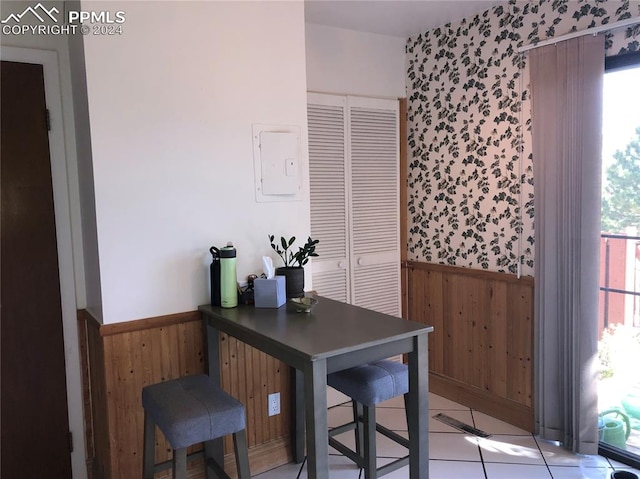 tiled office featuring wooden walls and electric panel