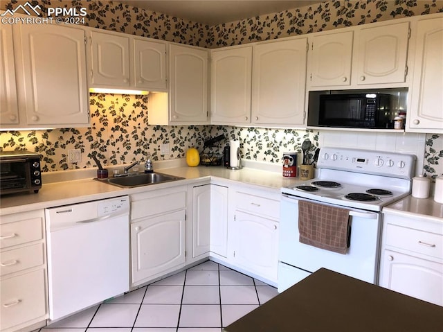 kitchen featuring white appliances, sink, light tile patterned floors, and white cabinets