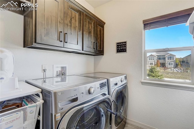 clothes washing area with cabinets and separate washer and dryer