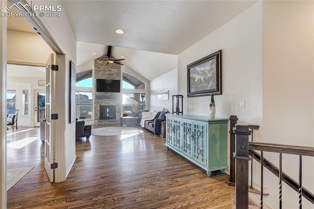 corridor with a textured ceiling, vaulted ceiling with beams, and dark hardwood / wood-style floors