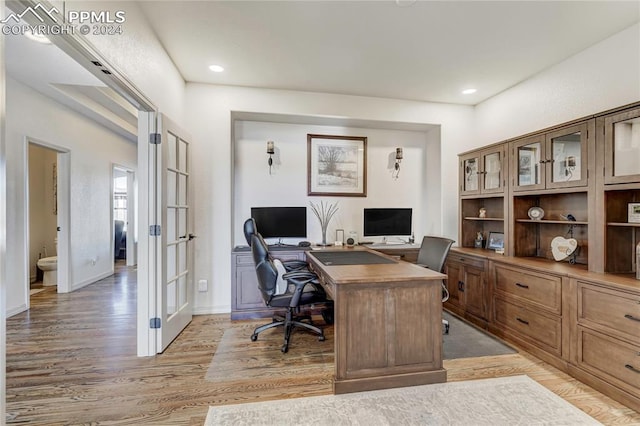 office with light wood-type flooring and french doors