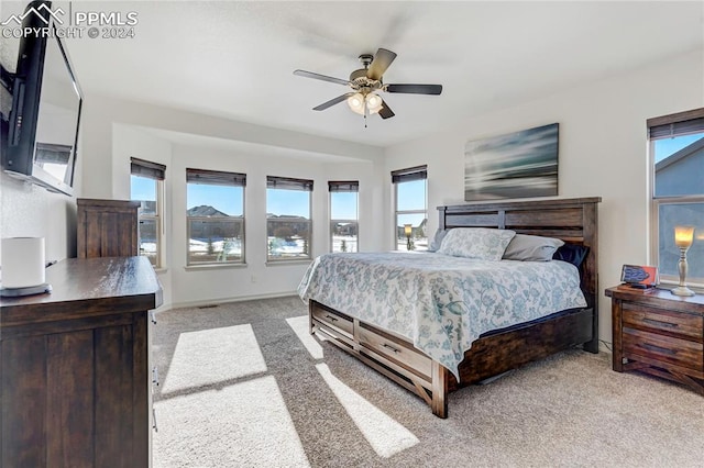 bedroom with multiple windows, ceiling fan, and light colored carpet