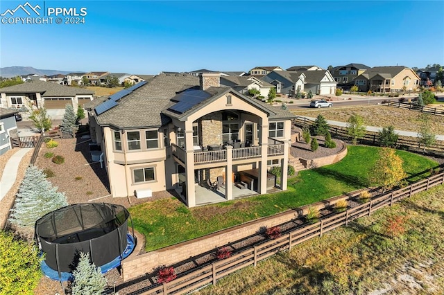 rear view of property with a patio, a balcony, and a lawn