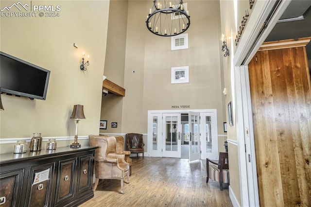 entrance foyer with a towering ceiling, wood-type flooring, and an inviting chandelier