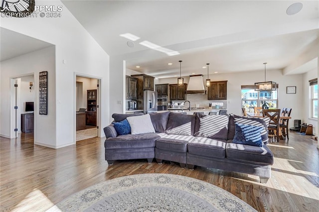 living room featuring lofted ceiling, sink, a chandelier, and dark hardwood / wood-style floors