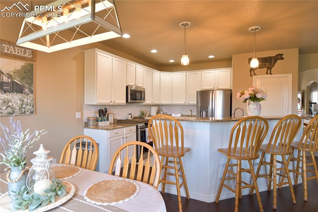 kitchen featuring pendant lighting, stone countertops, white cabinetry, stainless steel appliances, and dark hardwood / wood-style flooring