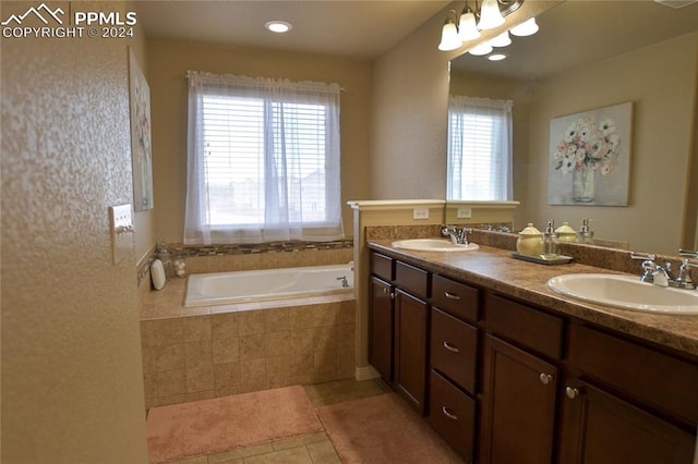 bathroom with vanity, a relaxing tiled tub, tile patterned floors, and a healthy amount of sunlight