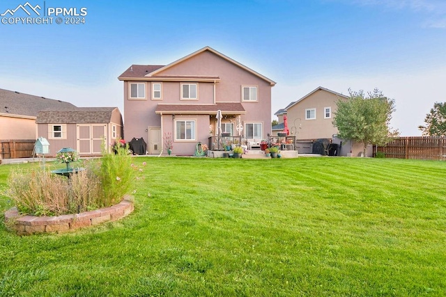 back of house with a patio, a yard, and a storage unit