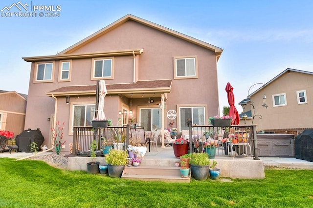 back of house featuring a hot tub, a deck, and a yard