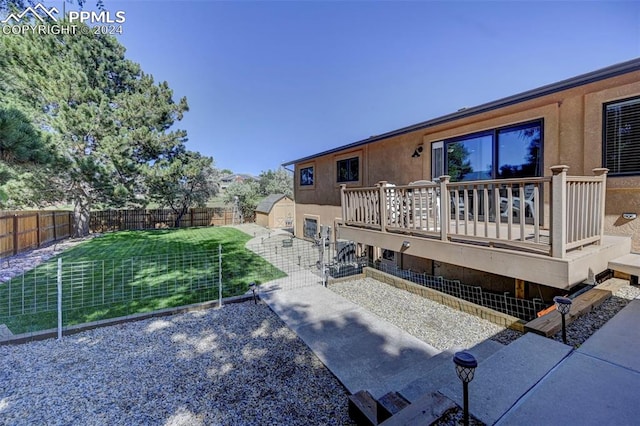 rear view of house featuring a wooden deck, a lawn, and a patio area