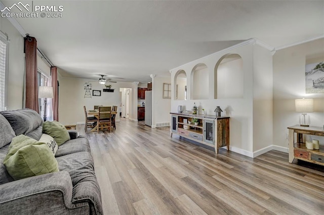 living room with light hardwood / wood-style floors, ceiling fan, and crown molding