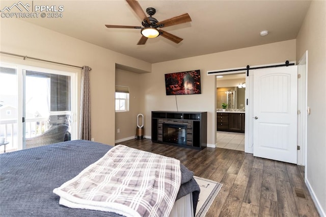 bedroom with ensuite bath, ceiling fan, dark wood-type flooring, and a barn door