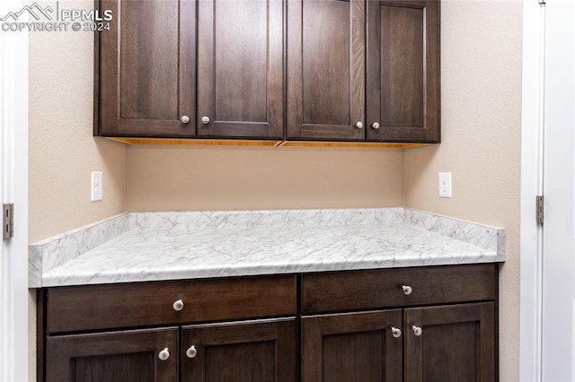 kitchen featuring light stone countertops and dark brown cabinets