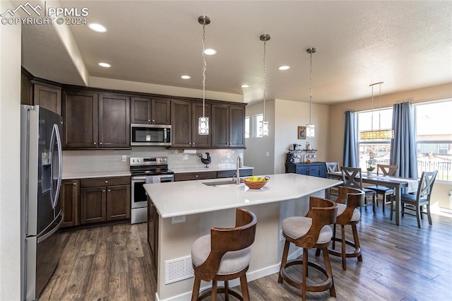 kitchen featuring appliances with stainless steel finishes, dark hardwood / wood-style floors, sink, and pendant lighting