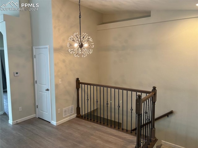 staircase featuring an inviting chandelier, vaulted ceiling, and hardwood / wood-style floors