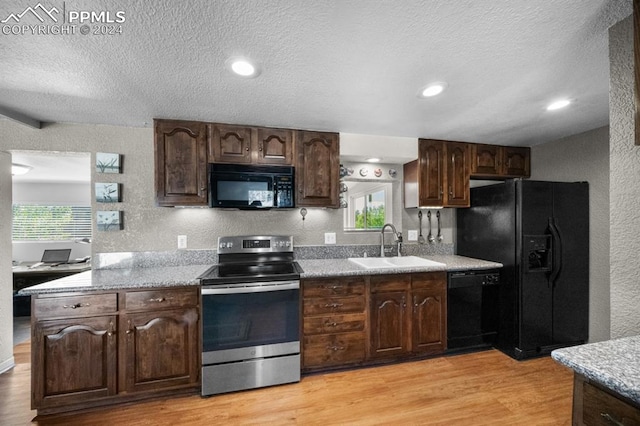 kitchen with sink, dark brown cabinets, a textured ceiling, light hardwood / wood-style flooring, and black appliances