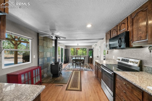 kitchen with light hardwood / wood-style floors, ceiling fan, stainless steel range with electric cooktop, and plenty of natural light