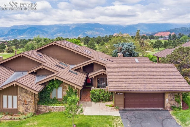 view of front of house featuring a mountain view, a garage, and a front lawn