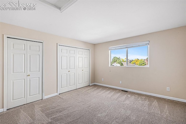 unfurnished bedroom featuring carpet floors and two closets